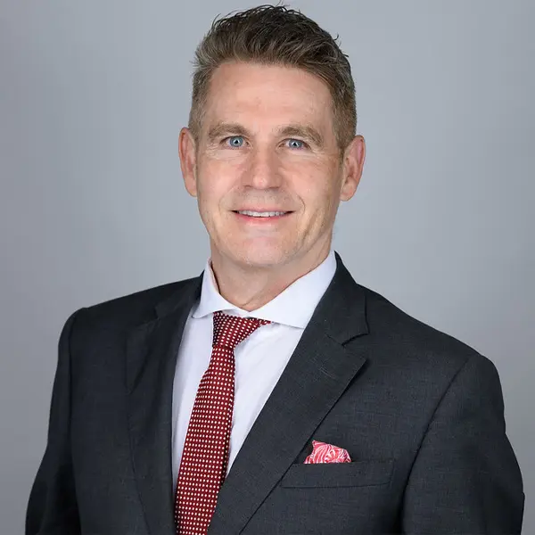 Headshot of Professor Peter Smith wearing a suit and red tie